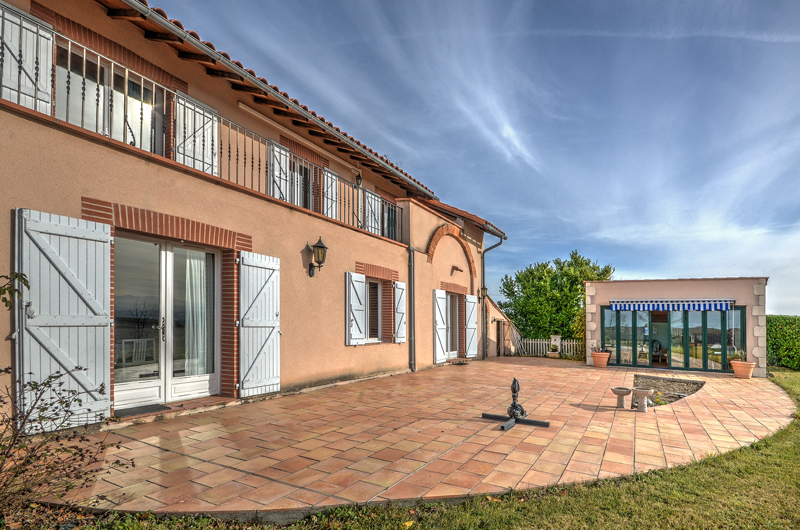 Front view of the house with paved terrace and sun room