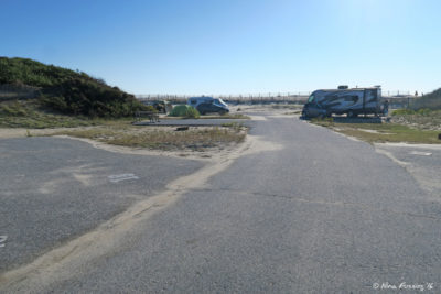 View down end of C loop. Empty site C18 on left with C16 behind. RV in C15 in back right.