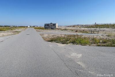 View down I loop on beach side. Empty site I84 on right with RV in I90 three sites behind.